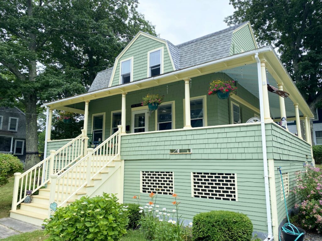 Green house with wrap-around porch.