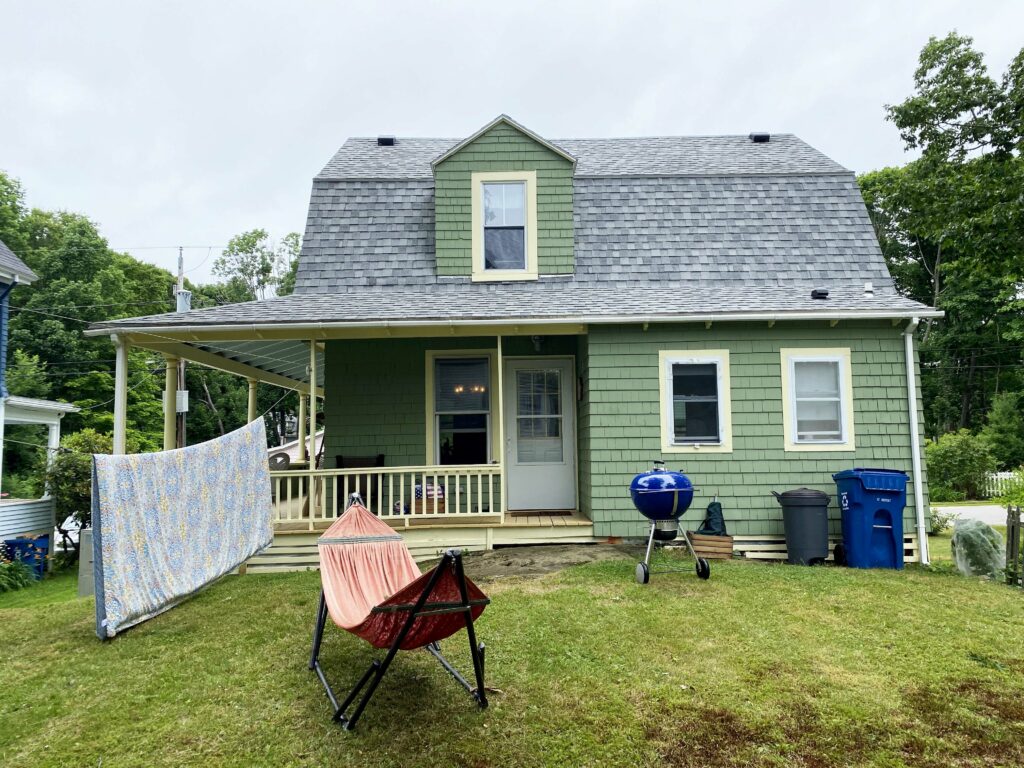 Back of the house with a hammock and grill in the yard.