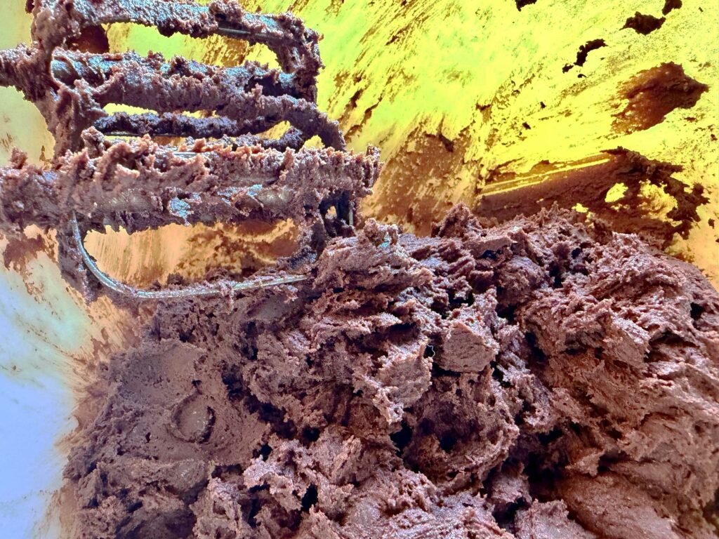 Dark chocolate cookie dough stuck to mixer in bowl.