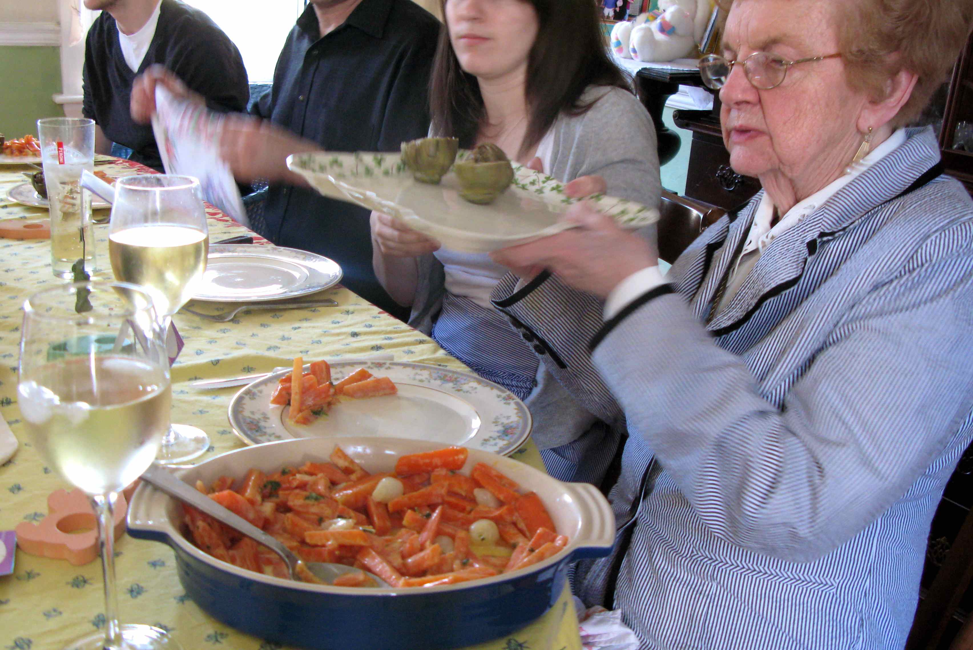 A woman passes a plate at a dinner table